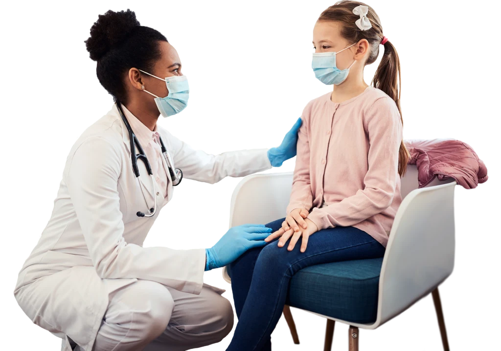 Masked doctor kneels down to talk with young masked patient sitting in a waiting room chair